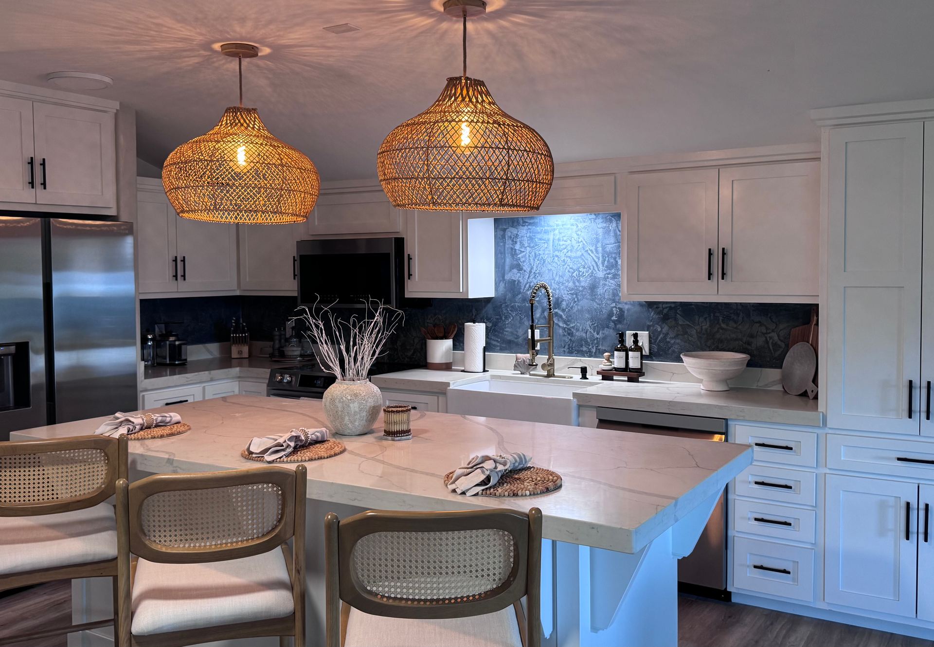 Kitchen with rattan pendant lights, white cabinets and a blue plaster backsplash
